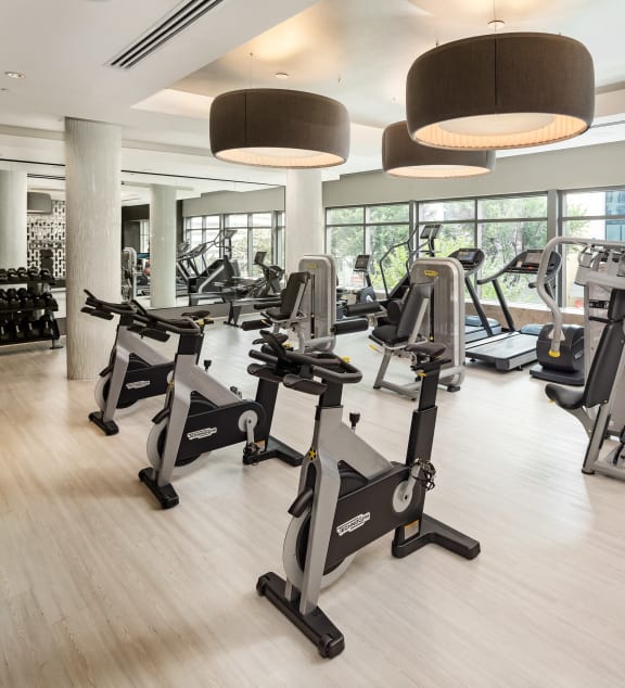 a gym with treadmills and other exercise equipment on a wooden floor