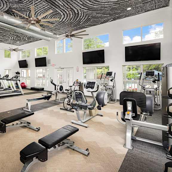A gym with a variety of equipment including treadmills, weights, and exercise machines.