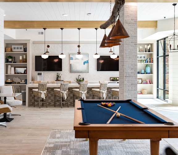 A billiard table is in the middle of a room with a white and wood floor.