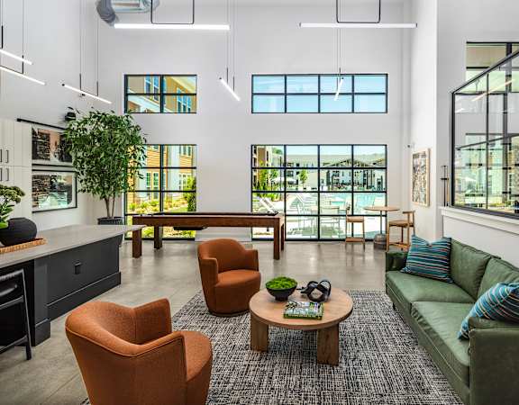 A modern living room with a green couch and orange chairs.