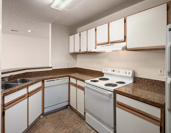 a kitchen with white appliances and granite counter tops and white cabinets