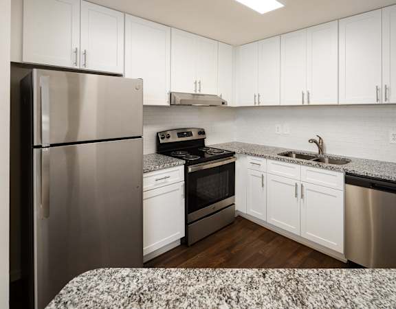 A kitchen with white cabinets and a stainless steel refrigerator.