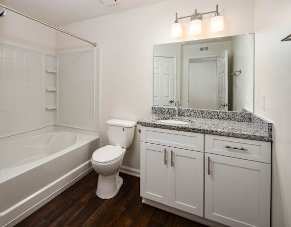 a bathroom with white cabinets and a toilet and a tub