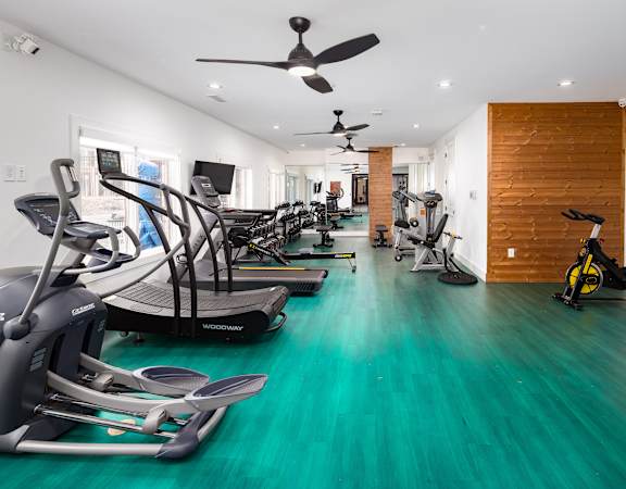 A room with a green floor and a row of exercise bikes.
