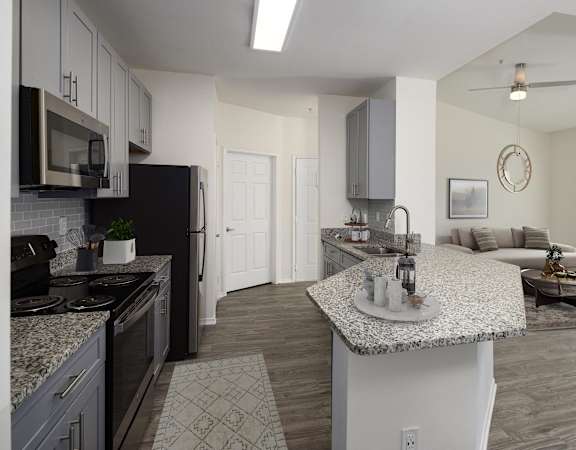 an open kitchen and living room with a marble counter top