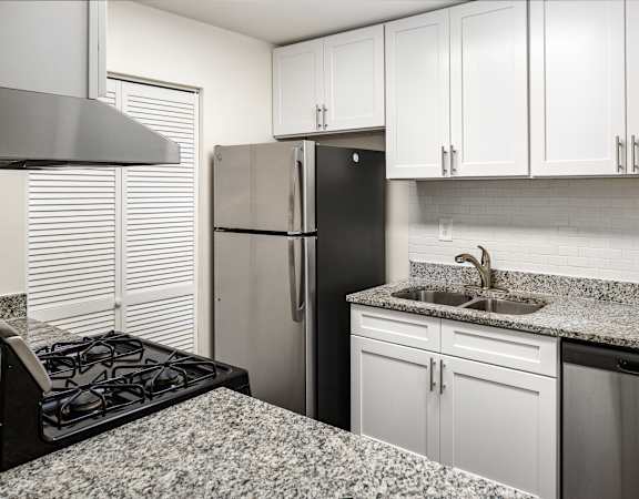 a kitchen with granite counter tops and a stainless steel refrigerator