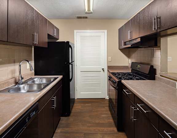 A kitchen with dark brown cabinets and a black refrigerator.