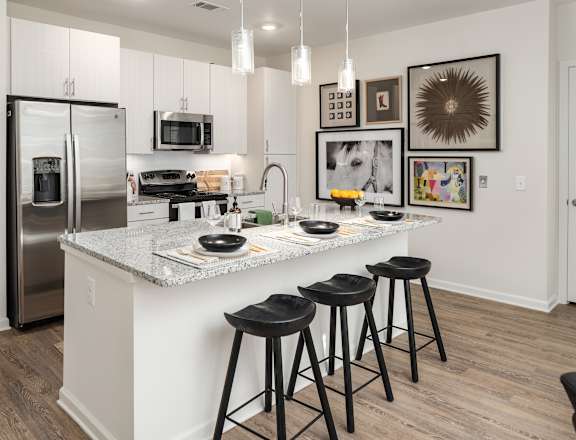 A kitchen with a white island and black stools.