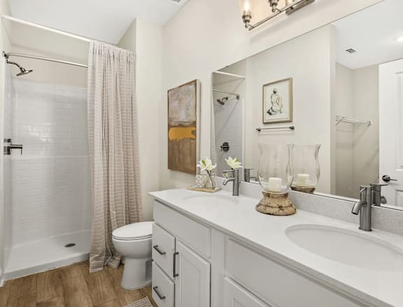 A white bathroom with a toilet, sink, and shower.