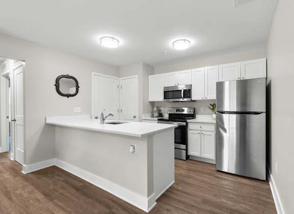 A kitchen with white cabinets and a stainless steel refrigerator.