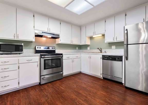 a kitchen with white cabinets and a stove and a ceiling fan