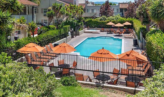 Studio Apartments in San Jose CA - Village of Taxco - Blue Pool, with Orange Umbrellas, Lounge Chairs, and Spa, with Surrounding Trees and Lush Greenery