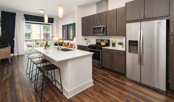 Modern Open Kitchen with Island Seating, Stainless Steel Appliances, and Wood-Style Flooring