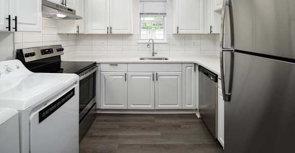 a white kitchen with stainless steel appliances and white cabinets