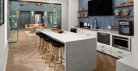 A modern kitchen with a bar area and a television mounted on the wall.