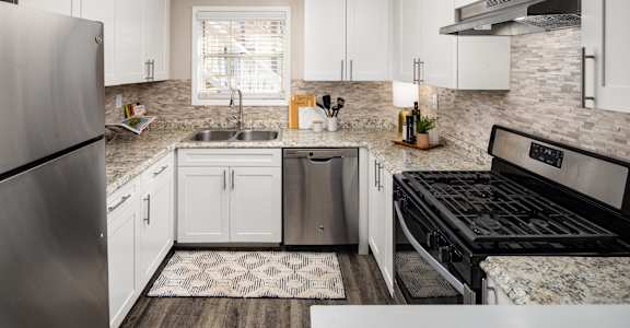 an updated kitchen with white cabinets and stainless steel appliances