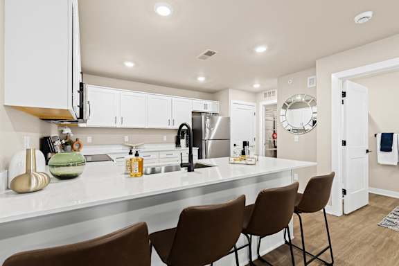 an open kitchen with a large counter with chairs and a sink