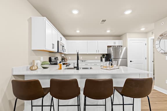 a kitchen with white cabinets and a large island with four chairs