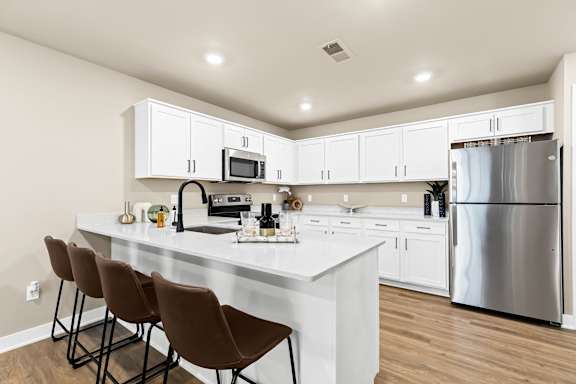 an open kitchen with a large island and stainless steel refrigerator