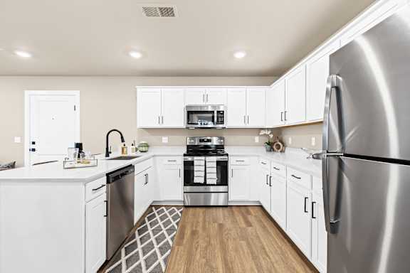 a large kitchen with white cabinets and stainless steel appliances