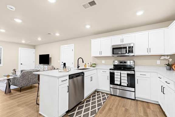 a large kitchen with white cabinets and stainless steel appliances