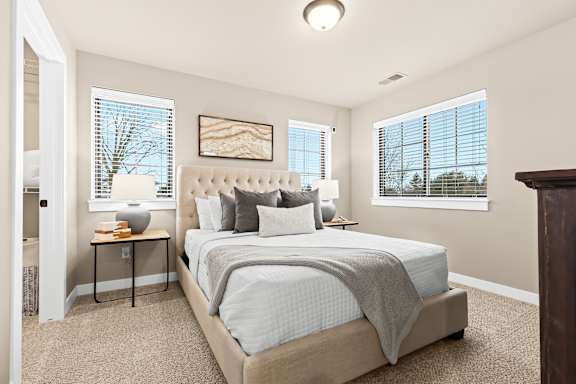 a bedroom with a large bed and two windows