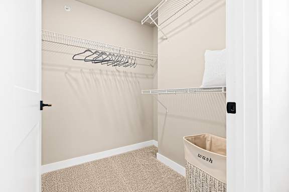 a walk in closet with a closet organizer and a laundry basket