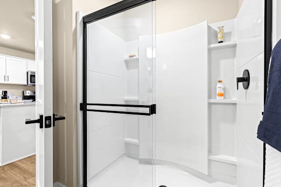 a shower with a glass door in a white bathroom