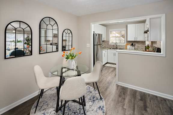 A kitchen with a table and chairs in the foreground and a refrigerator in the background.