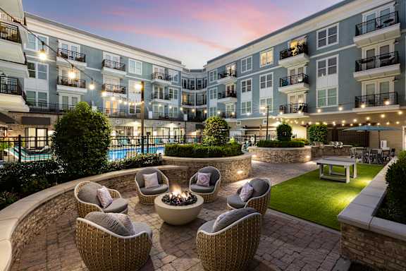 an outdoor patio with chairs and a fire pit at dusk