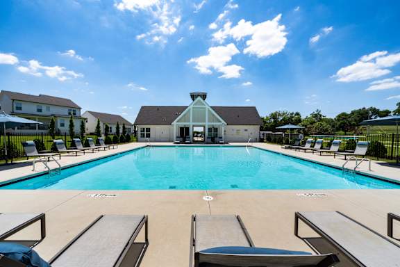 A swimming pool with lounge chairs and a building in the background.