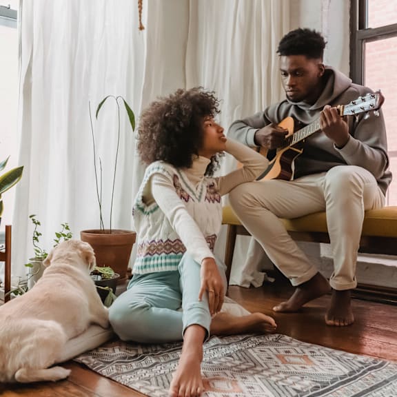 a man playing a guitar and a woman sitting on the floor with a dog at Chinoe Creek Apartments in Lexington KY