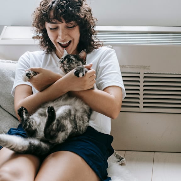 a woman sitting on a couch holding a cat at Chinoe Creek Apartments in Lexington KY
