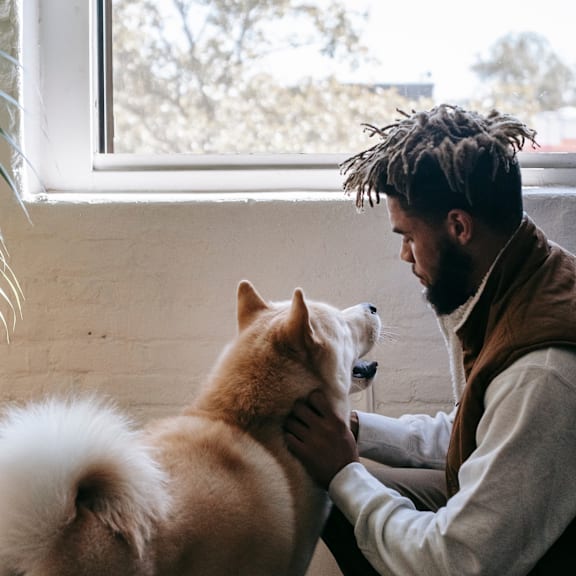 a man with his dog in front of a window at The Resort At Lake Crossing  Apartments, PRG Real Estate, Lexington