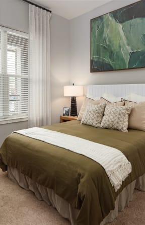 a bedroom with a bed and a large green painting