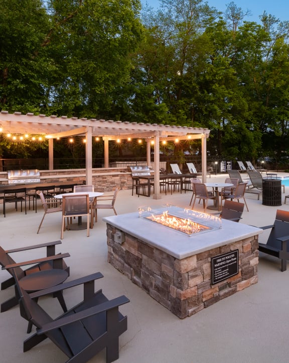 a patio with a fire pit and a pool with chairs and tables