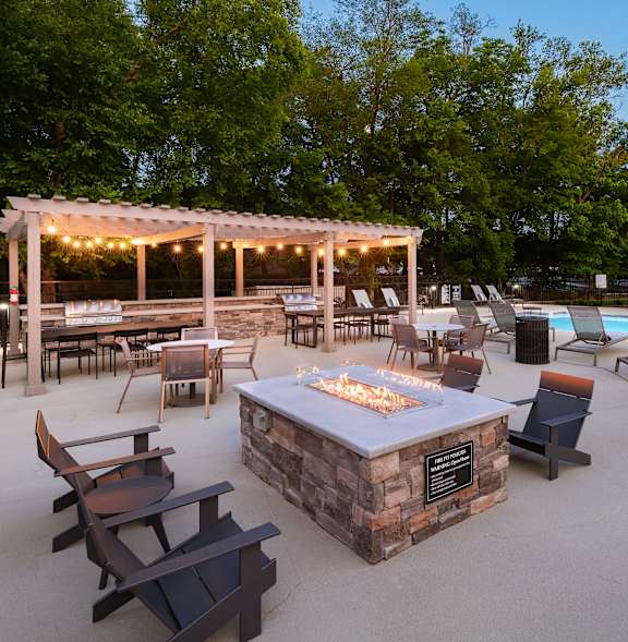 A patio with a fire pit and chairs.