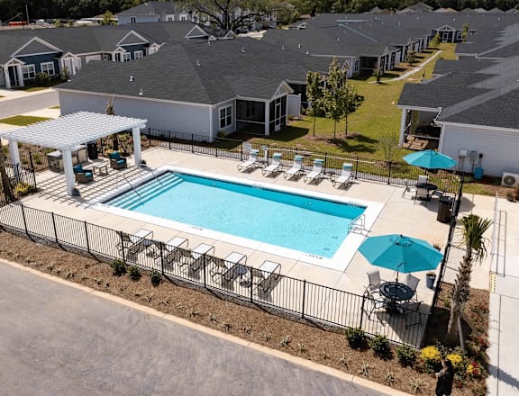 A swimming pool surrounded by a black fence and chairs.