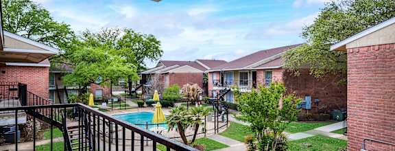 A view from a balcony overlooking a pool and apartment buildings.