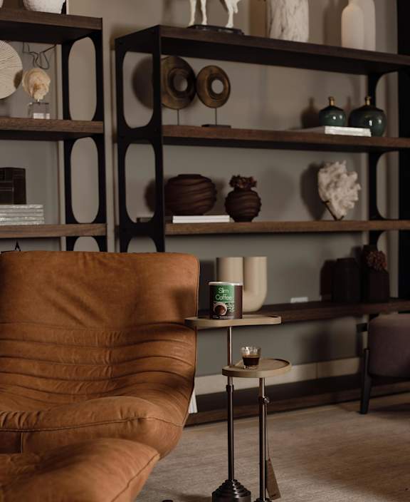 A brown leather chair sits in front of a shelf with various decorative items.