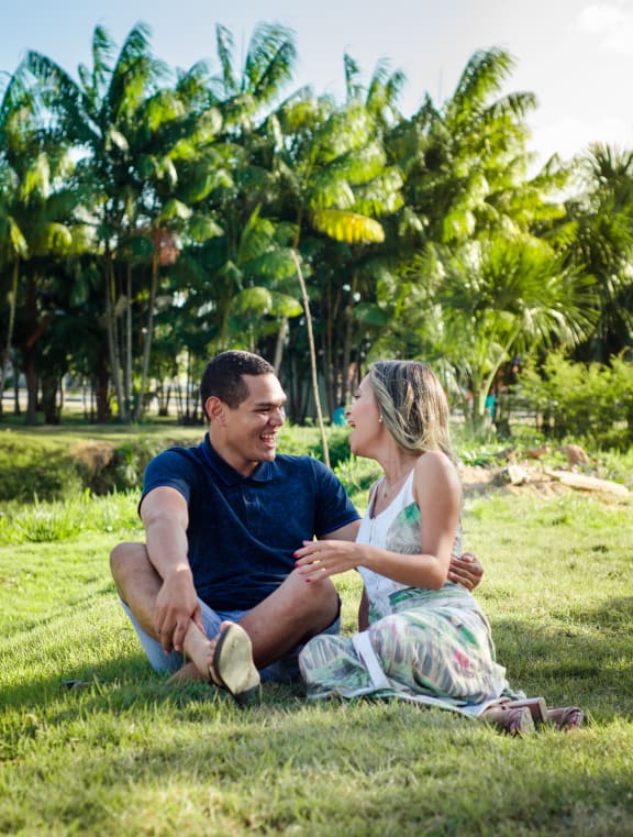 a couple sitting in the grass on a sunny day