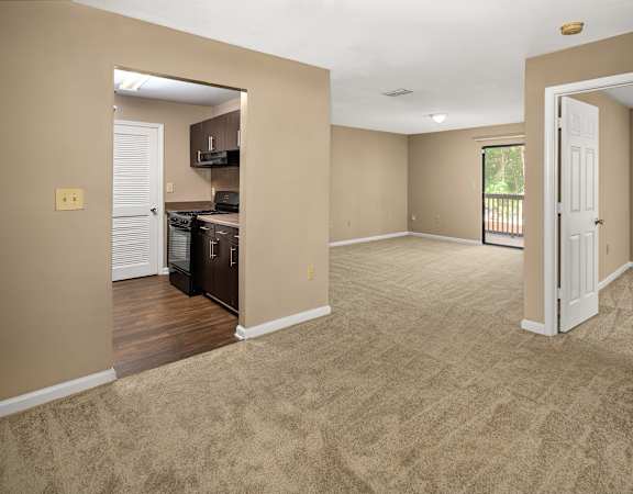 A spacious living room with a kitchen area in the background.