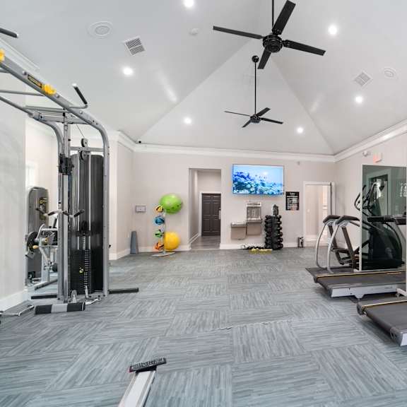 A spacious gym with a variety of equipment including treadmills, weights, and a television.