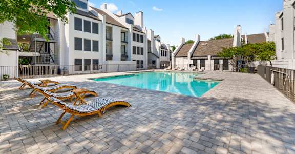 a swimming pool with lounge chairs in front of an apartment building