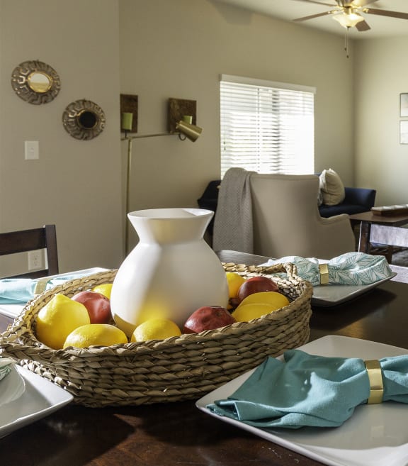 an open concept living room and dining room with a table with a pitcher and fruit on it