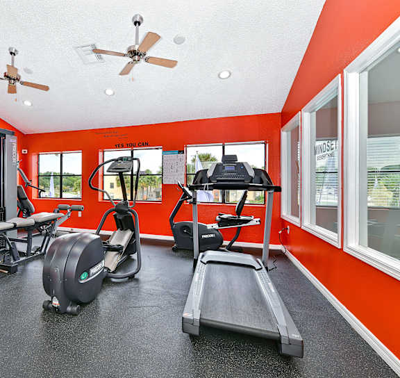 a workout room with red walls and exercise equipment