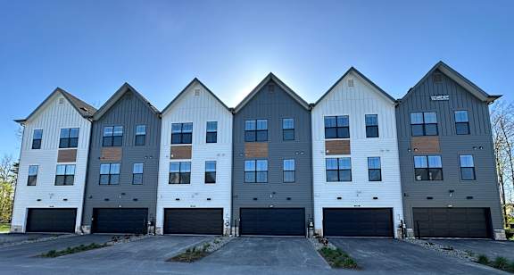 an empty parking lot in front of three buildings with garages at The BLVD at Wilson Crossings, Wyoming Michigan