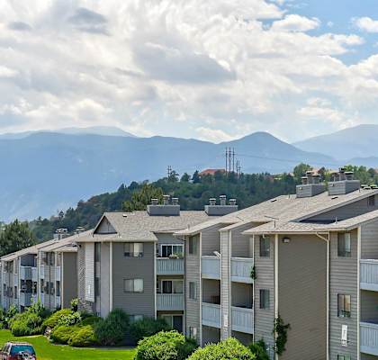 a row of apartment buildings on a street with mountains in the background