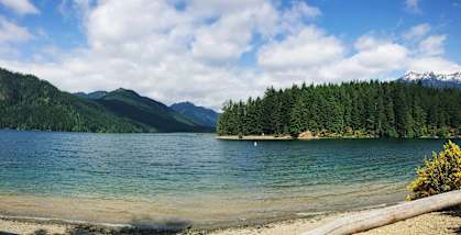 a lake with a forest and mountains in the background