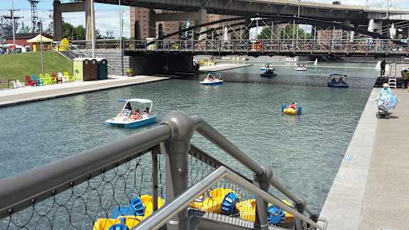 A view of a river with boats and a bridge in the background at The Lofts at Elk Terminal Apartments, Buffalo, 14204